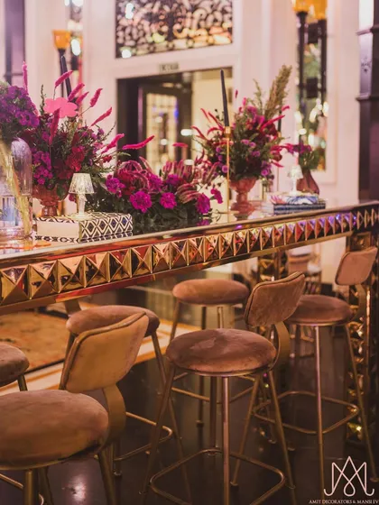 Another angle of the contemporary bar setup, highlighting the sleek bar stools and the intricate, geometric design of the gold bar front.