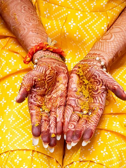 A close up of the bride's hands, adorned with intricate mehendi and covered in haldi.