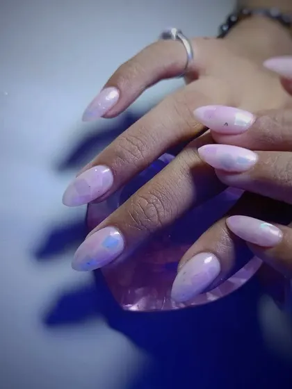 A pretty set of almond-shaped nails with a soft, iridescent pink polish.
