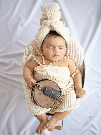 A touch of luxury for this little one. This sleeping newborn is styled with pearls and a designer-inspired bag for a unique and fashionable portrait.