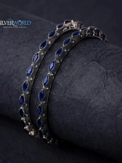 A darker, moodier shot of the blue enamel silver bangles, highlighting their deep color and sleek design.