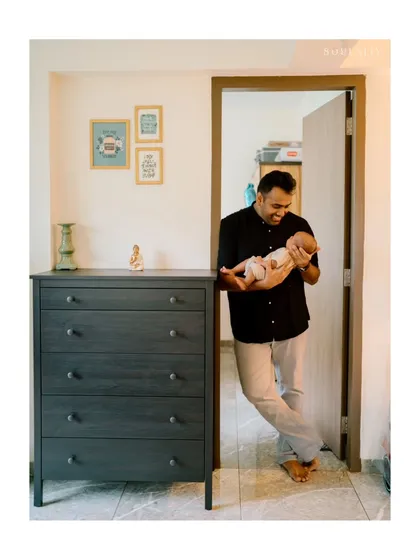 A lifestyle newborn session at home allows for beautifully natural moments. Here, a proud father holds his baby in the doorway of their nursery, a candid portrait filled with warmth and love.