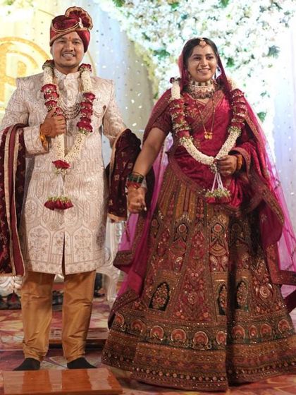 A happy couple, hand in hand on their wedding day. The bride's traditional red lehenga is a perfect match for the groom's elegant sherwani.