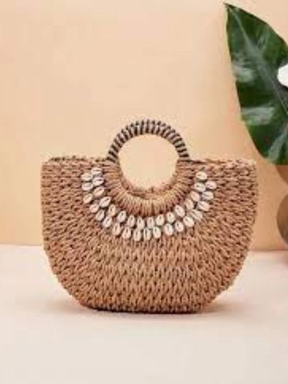 A beautifully crafted woven bag decorated with natural cowrie shells. This piece perfectly captures our mission to empower handicraft workers while promoting sustainable fashion that is both stylish and deeply connected to nature.