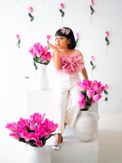 Blowing a kiss to the camera, this stylish five-year-old is a natural model. The minimalist setup with bright pink tulips makes her outfit and personality pop.