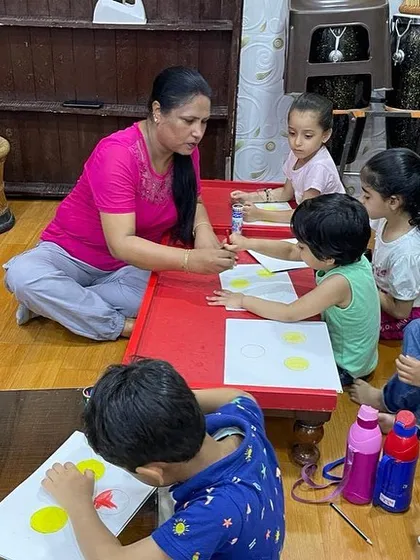 I believe in getting down to the children's level. Here I am helping a group of our youngest students with a painting activity.
