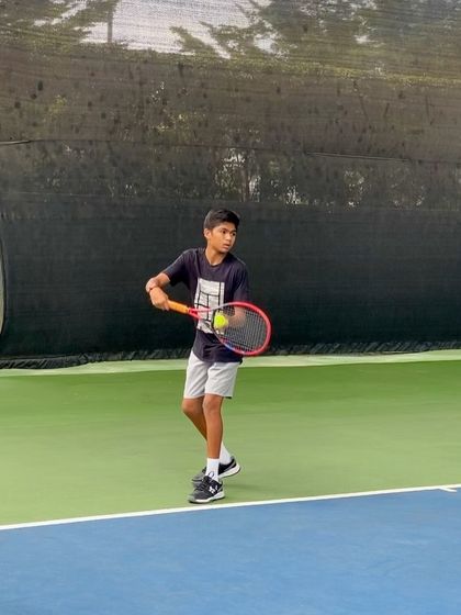 A young player practices his service motion during a training session. We dedicate significant time to developing a powerful and consistent serve, a crucial weapon in tennis.
