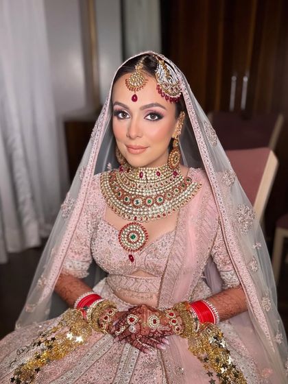 A beautiful portrait of the bride, showcasing her flawless, glowing makeup. The soft pink and purple tones on her eyes harmonize perfectly with her intricate jewelry and pastel outfit.