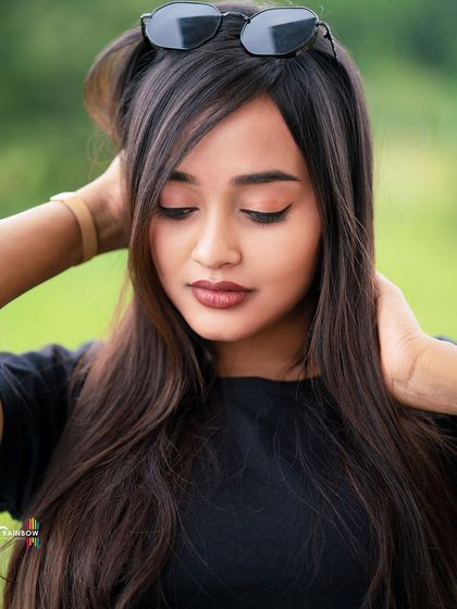 A close-up beauty shot of a model in a casual black t-shirt, focusing on her makeup and expression.