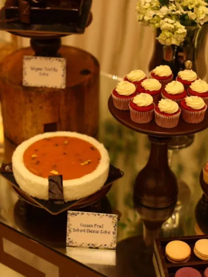 A dessert table featuring a passion fruit cheesecake and red velvet cupcakes. We offer a wide range of cakes and pastries to create a diverse and tempting dessert spread for any event.