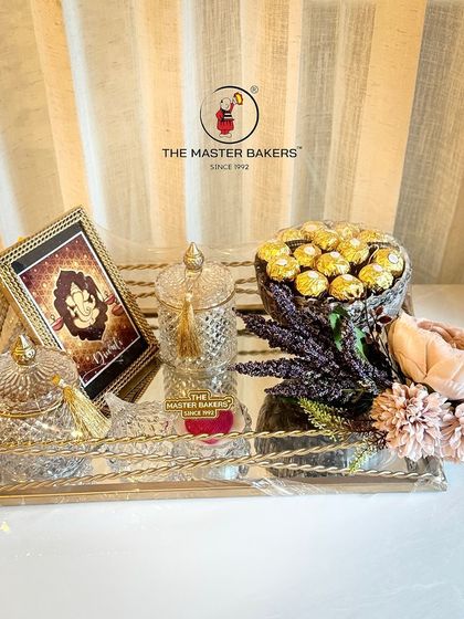 This luxurious hamper combines the best of our offerings. It features an elegant frame, a bowl of assorted chocolates, and crystal jars for dry fruits, beautifully arranged with lavender and flowers on a mirrored tray.