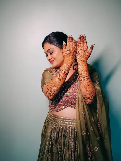A joyful portrait of the bride showing off her elaborate mehndi design. Her happy expression and the beautiful henna art tell a story of celebration and tradition.