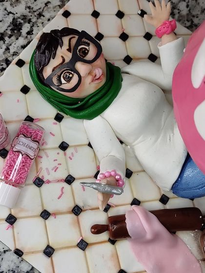 A detailed shot of my caricature figurine, seemingly crushed under the weight of a giant cake.