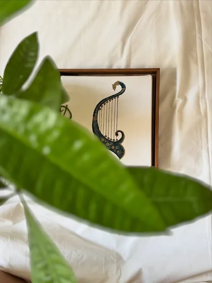 'The Twenty-Fifth Note' series explores the connection between music and spirituality. This miniature painting of a harp, seen through a leaf, hints at the silent, soulful note beyond creation.