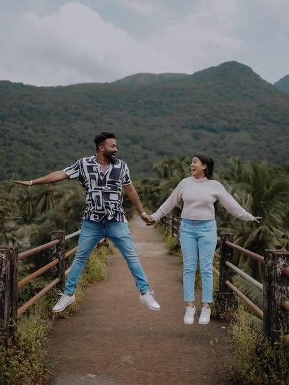 A fun, energetic shot of a couple jumping on a bridge with a lush green valley in the background. This photo perfectly captures the joy and spirit of an adventurous couple.