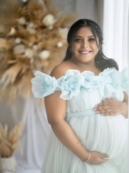 A lovely close-up portrait of the mom-to-be. The soft window light illuminates her face, highlighting her joyful expression and pregnancy glow.