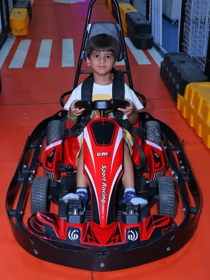 A young boy confidently takes the wheel of his red go-kart, ready for a fun race around our specially designed track.