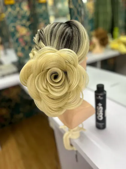 A close-up of a perfectly formed rose bun, showing the detailed layering technique. This is created on a mannequin to showcase the precision of the style.