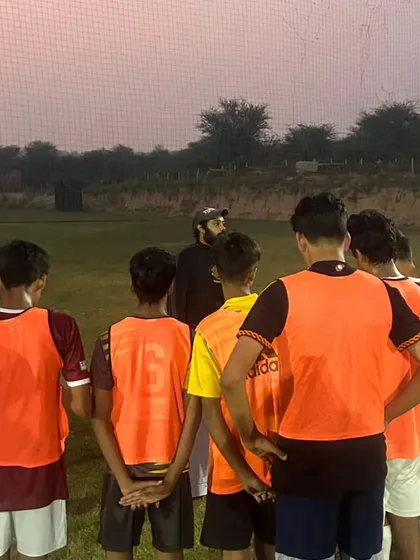 A coach gives a team talk during a break in training. These moments are crucial for reinforcing tactical instructions and keeping the team focused.