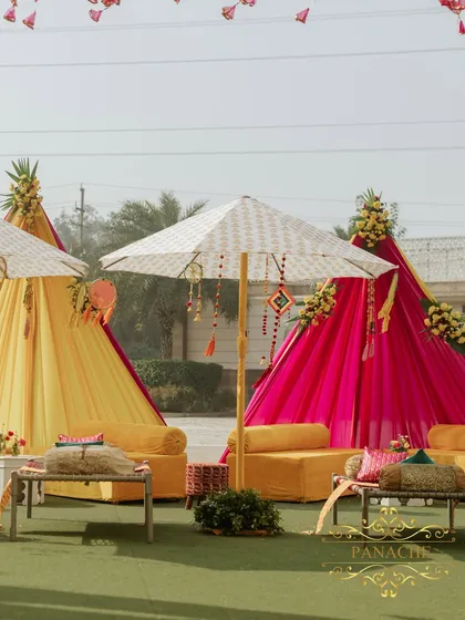 A wider view of the lounge areas, featuring teepee-style canopies in bright pink and yellow fabrics. This adds a modern, bohemian touch to the traditional Punjabi Haldi decor.