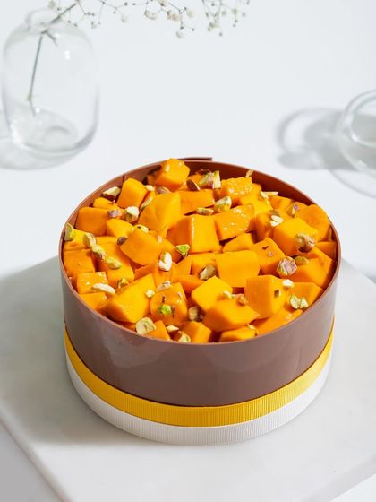 A close-up of the mango cake, showing the generous topping of fresh mango and pistachios.