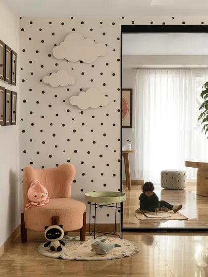 This corner of the clinic features a whimsical polka-dot wall with cloud-shaped lights. A comfortable, child-sized armchair and soft toys create a cozy nook for a child to relax and feel at ease.