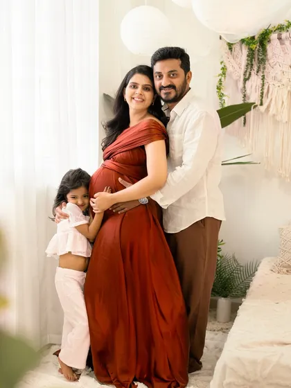 A complete family portrait filled with warmth and excitement. The parents and their daughter embrace the baby bump in this lovely, natural-light studio session.