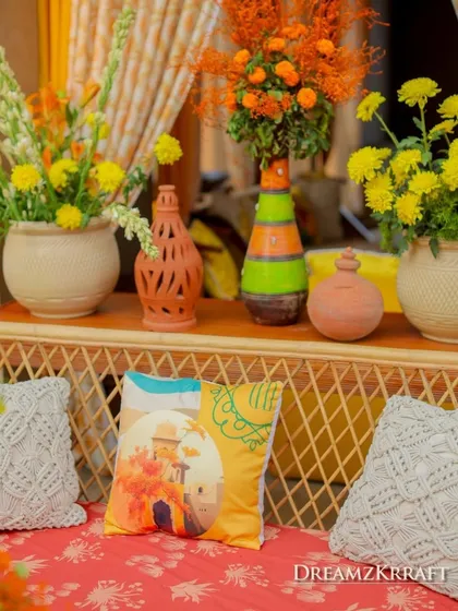 Thematic decor details for a 'Turmeric & Zataar' Haldi, featuring custom-printed cushions and earthy pottery. I weave the event's theme into even the smallest elements.