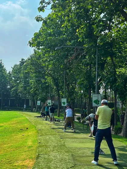 A long line of golfers fills the range, taking advantage of a beautiful day to work on their game.