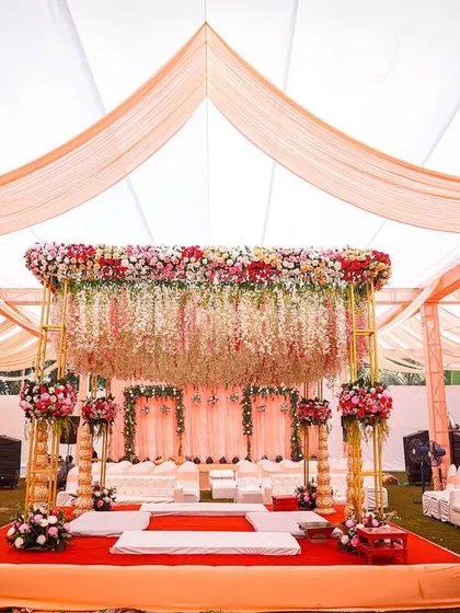 A frontal view of the beautiful floral mandap. The combination of the draped ceiling and the lush flower arrangements creates a grand yet intimate space for the wedding vows.