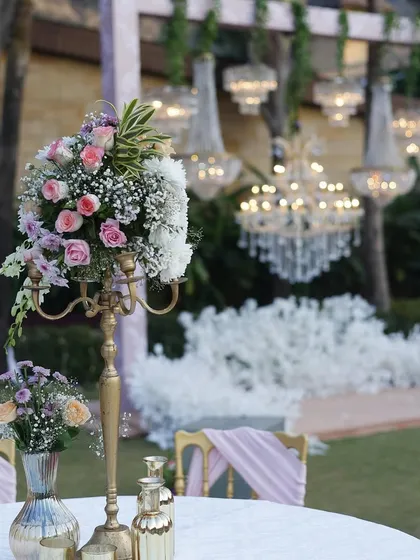 A beautiful table centerpiece with a vintage candelabra and a mix of pastel flowers, with grand chandeliers in the background.