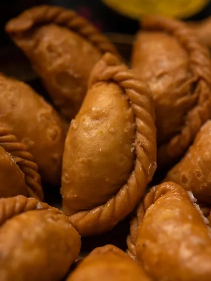 A close-up macro shot of a Gujjiya. This allows the viewer to appreciate the texture and craftsmanship of the sweet, making it look even more delicious.