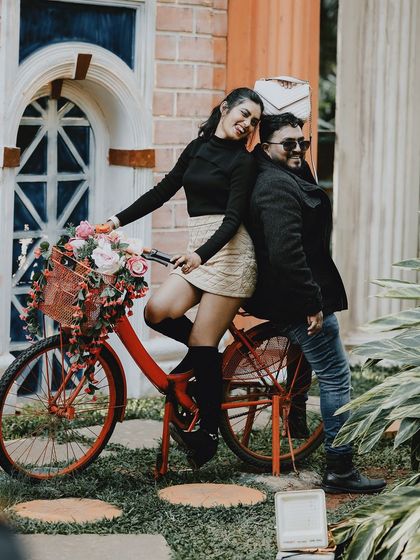 A fun and stylish pose with the bride sitting on a decorated red bicycle, creating a chic, vintage-inspired photo.