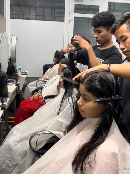 A busy day in the classroom, with students practicing haircuts on live models under the supervision of our expert trainers.
