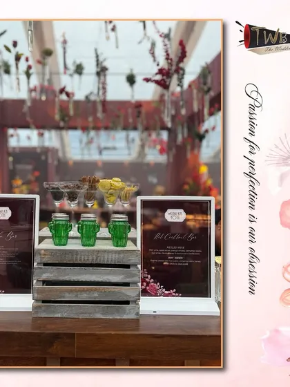 A rustic and chic bar corner with wooden crates, framed menus, and cactus-shaped glasses, showcasing our attention to thematic details for a 40th birthday in Udaipur.