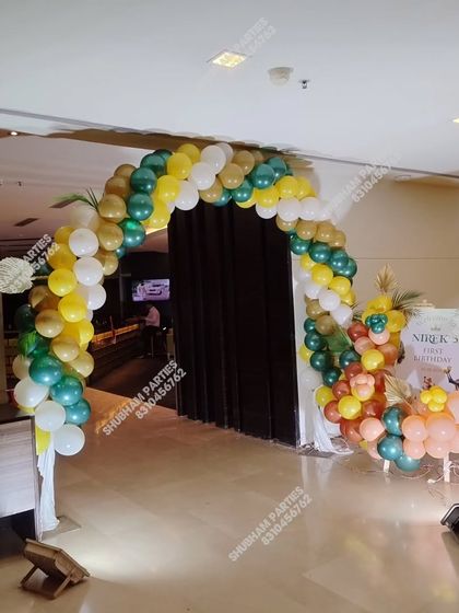 A stylish balloon arch at the entrance of a party hall for a jungle-themed event.