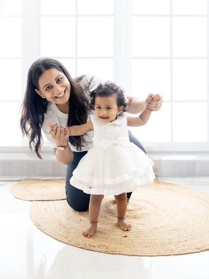 A mother helps her daughter take her first steps. A precious milestone captured during a family session.