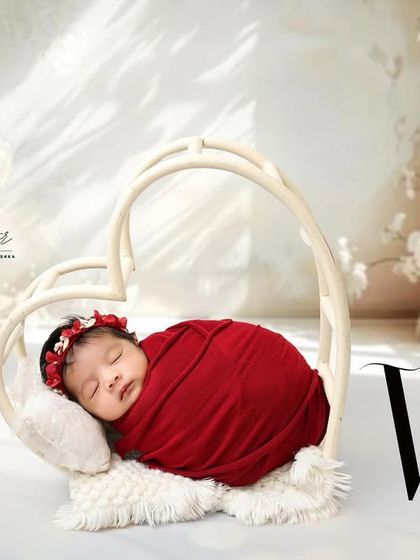 Wrapped in love. This beautiful shot features a newborn in a vibrant red swaddle, nestled inside a heart-shaped prop for a simple yet powerful statement.
