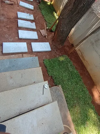 The turf installation is progressing up the path. This method ensures a seamless and professional finish.