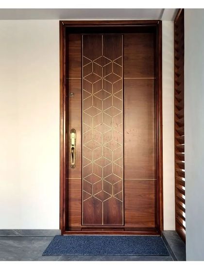 A main door with a geometric brass inlay pattern on polished wood, demonstrating our ability to blend traditional materials with modern design motifs.