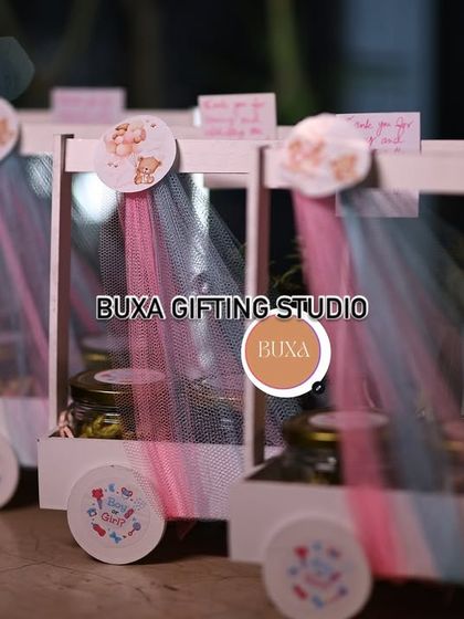 A close-up of the baby shower hamper carts, showing the custom "Boy or Girl?" stickers on the wheels and jars.