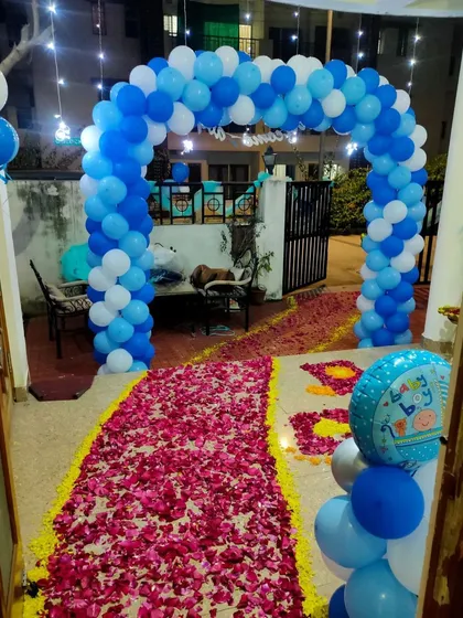 The entrance for the "Welcome Baby Boy" party, featuring a blue and white balloon arch and a pathway of rose petals.