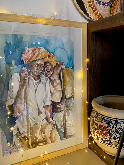 My painting "In Leisure" framed and displayed in a cozy corner of my home. The warm fairy lights add to the serene mood of the artwork.