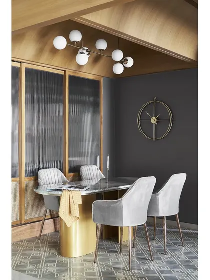 The bespoke dining table features a botanic green marble top and brass-cladded supports, set on geometric cement tiles. This combination of materials adds a layer of luxury and custom detail.