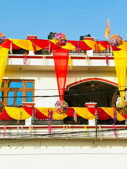 A daytime view of the house exterior decoration. The combination of red and yellow drapes with decorative hangings looks just as vibrant and festive in the sunlight.