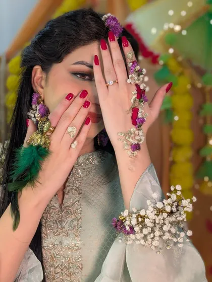 A playful shot showing off the details of the floral jewelry and the bright red nails, which add another pop of color to the overall Haldi look.