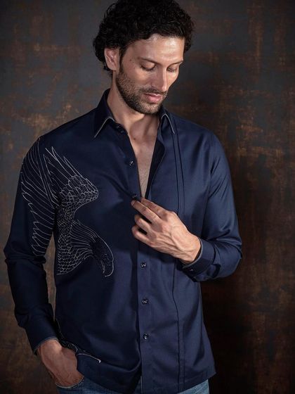 A navy shirt with a striking silver embroidered bird design. This exquisite detail elevates a classic shirt into a piece of wearable art.