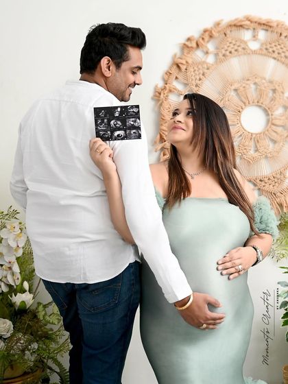 A creative way to share the journey. The mom-to-be holds up their sonogram pictures, a beautiful and personal touch for a couple's maternity portrait.