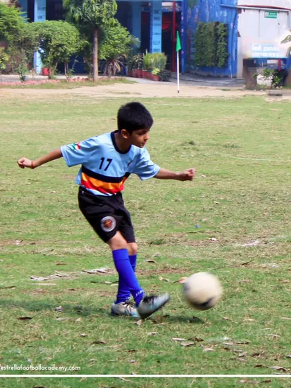 A young player practices his shooting technique on a grass field, focusing on generating power and accuracy.