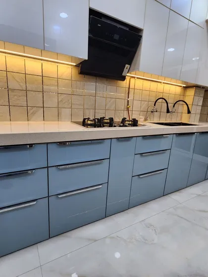 A close-up of the cooking area in the blue and white acrylic kitchen. The design features multiple drawers for easy access to pots and pans.
